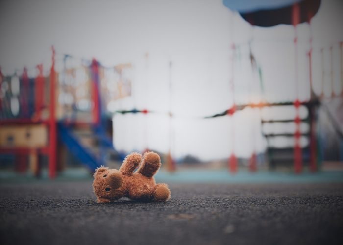 Lost teddy bear toy lying don on playground floor