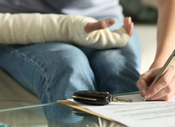 Lady with broken arm signing insurance document after car accident MAIN