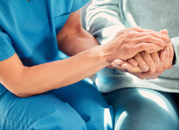 Nurse holding elderly patient hand