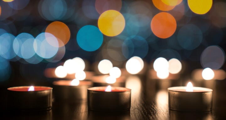 Several small lighted memorial candles on a darks background