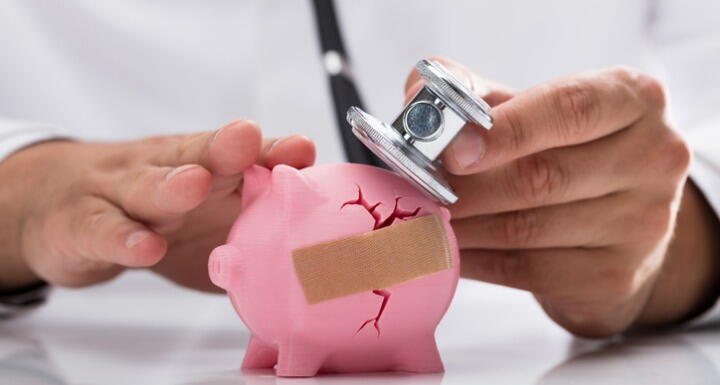 doctor examining cracked piggy bank with bandaid