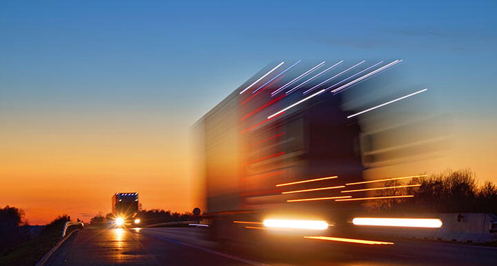 Headlights of big rig truck driving down the highway at dusk